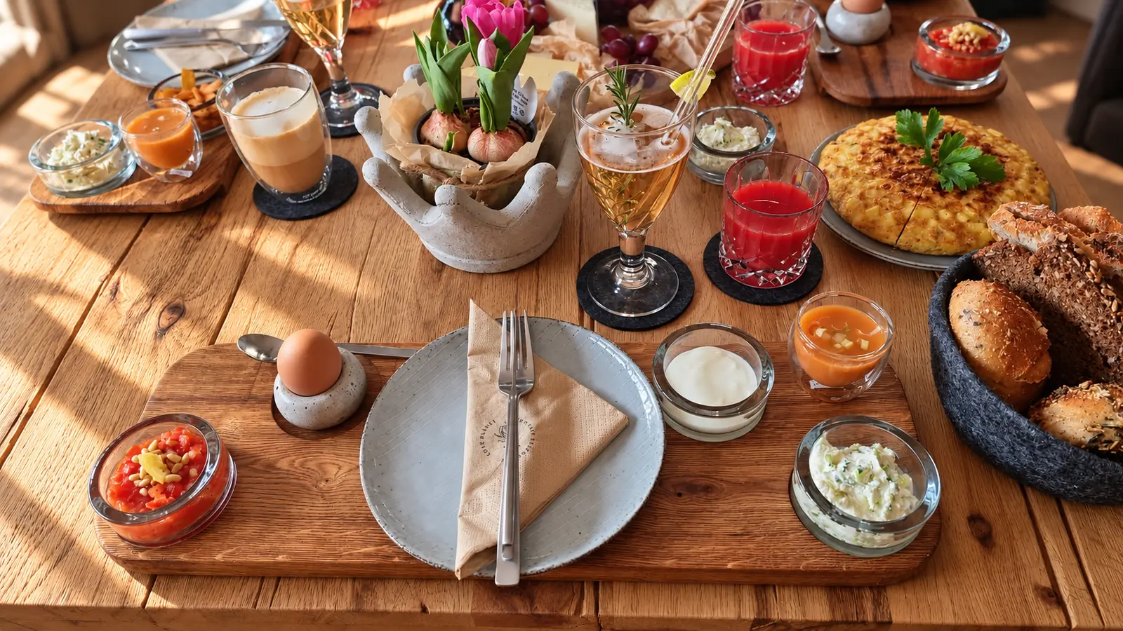 Nahaufnahme eines Tapasbretts aus Eiche mit grauem Teller, Ei und kleinen Glasschälchen